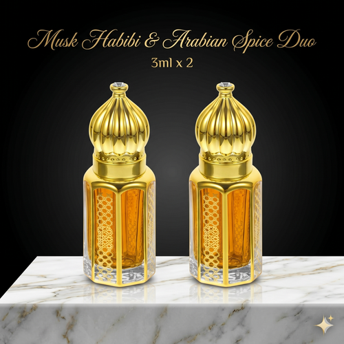Two gold and amber glass bottles labeled 'Musk Habibi & Arabian Spice Duo' on a marble surface with a black background.